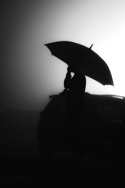 垂直剪影拍摄一个哭泣的人与伞附近的汽车图片下载