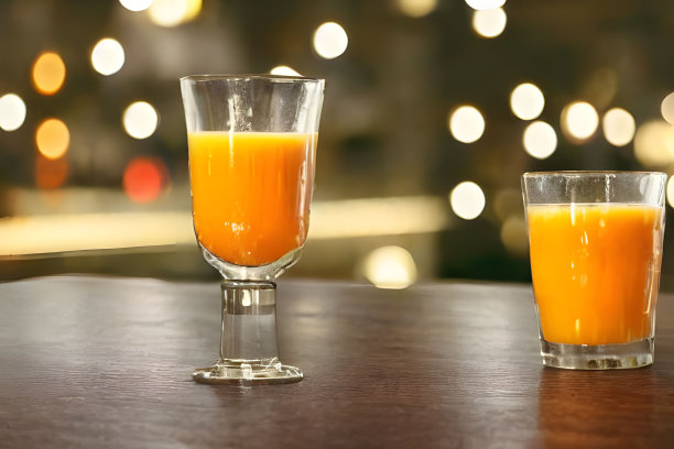 木桌上放着几杯胡萝卜汁，背景是散景灯图片下载