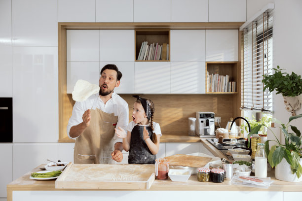 迷人的女儿孩子与惊讶的情绪拍手观看呕吐过程。快乐的爸爸爸爸教女儿揉面擀面准备做饭烤自制的披萨图片下载