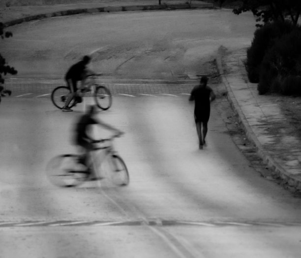 一个慢跑者沿着一条空旷的弯曲道路跑步，两个骑自行车的人跟着他图片下载