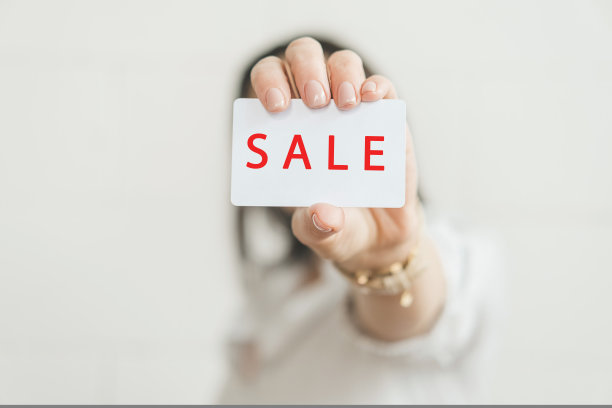 女性手中写着SALE字样的信用卡。素材图片