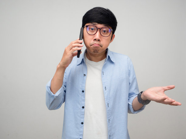 亚洲男子戴眼镜使用手机感到困惑和孤立图片下载