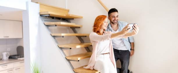 可爱、年轻、幸福的小情侣在家里的楼梯上一起自拍图片下载