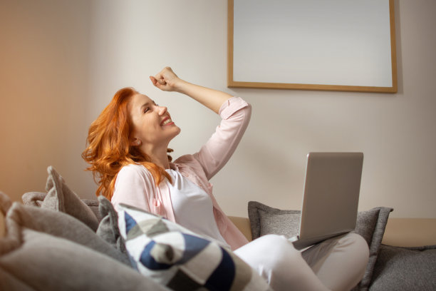 年轻兴奋的姜色女子握着拳头庆祝成功。快乐的女人庆祝胜利。图片下载