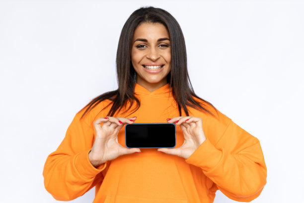 年轻的西班牙妇女微笑着展示智能手机屏幕图片下载