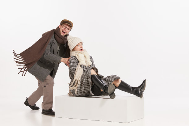 欢快的年轻人的肖像，男人和女人在冬天的衣服在一起玩，雪橇在白色的背景图片下载