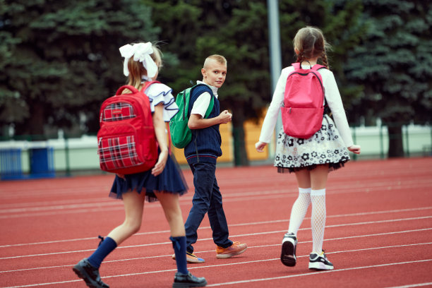 开始。回到学校，孩子和教育理念。男孩和女孩穿着校服，像小学生一样背着大背包在体育馆的跑步机上跑步。图片下载