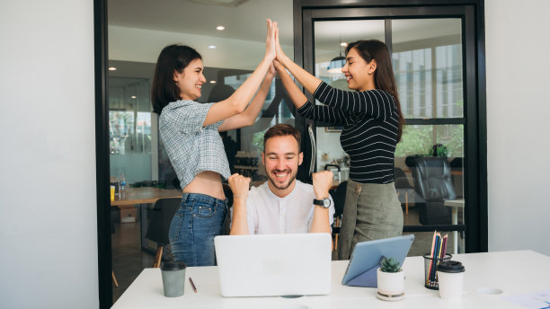 一群快乐、成功的商人一边笑着庆祝自己的成就，一边击掌庆祝。图片下载