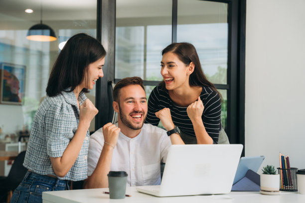 一群快乐、成功的商人一边笑着庆祝自己的成就，一边击掌庆祝。图片下载