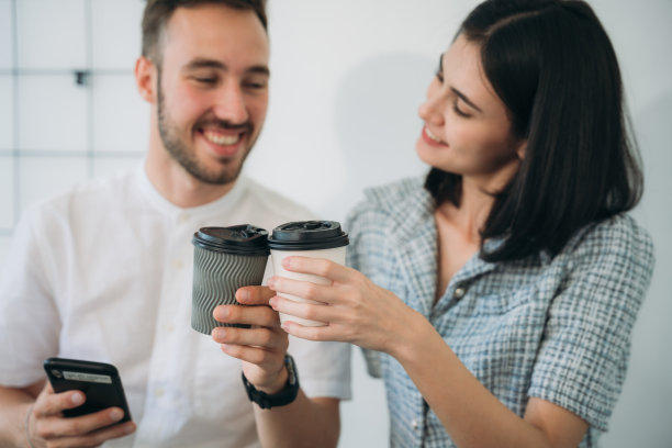 几个愉快的同事站在工作场所，端着咖啡交谈。图片下载