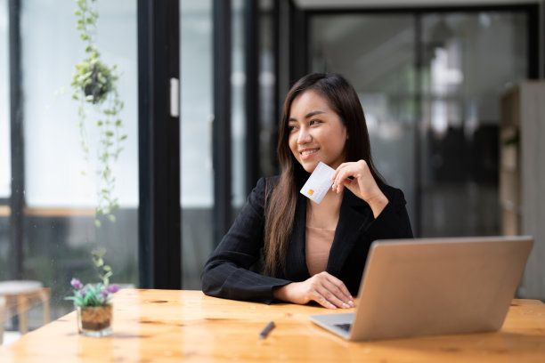 年轻的亚洲妇女为移动银行制作笔记本电脑，用信用卡在网上购物。图片下载