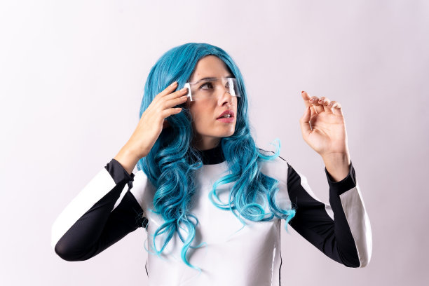 未来主义的概念，一个年轻女子的肖像蓝头发，夜光眼镜和银河赛博朋克服装。向右看图片下载