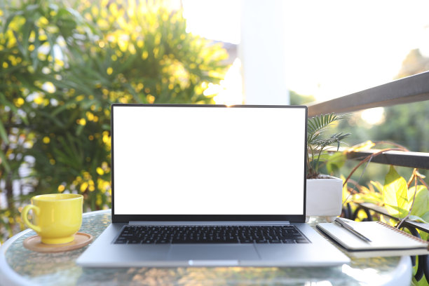 笔记本电脑前视图和黄色咖啡杯笔记本电脑在白色玻璃表户外阳台图片下载