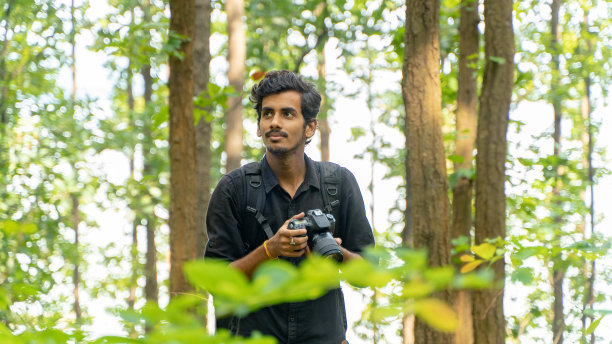 年轻的摄影师站在大自然中，用专业的相机拍照图片下载
