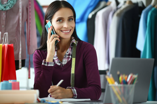 有吸引力的经验丰富的女裁缝在工作场所在工作室打电话给客户图片下载