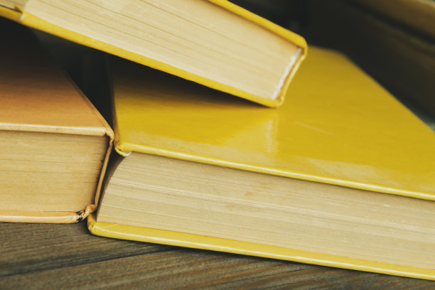 一张木桌上放着黄色的书。桌上放着学习用的书。从角度拍摄的照片。移了视线——桌上的书。黄色封面的书。图片下载