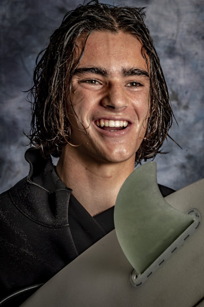 一个年轻人准备带着冲浪板去冲浪。图片下载