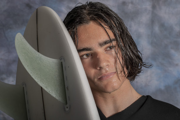 一个年轻人准备带着冲浪板去冲浪。图片下载