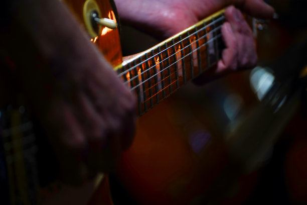 吉他手在一间黑屋子里弹吉他。吉他手的手正在弹吉他图片下载