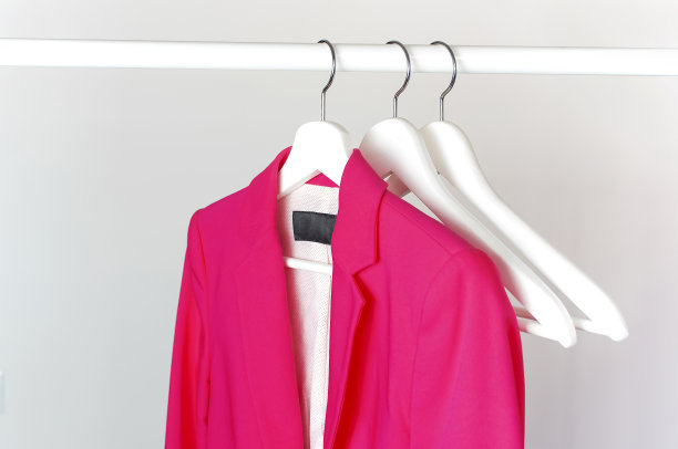 亮粉色的女子夹克在白色的木制衣架上杆对浅灰色的墙平铺复制空间。时尚夹克，女装潮流服饰，时尚背景。存储的概念,销售图片下载