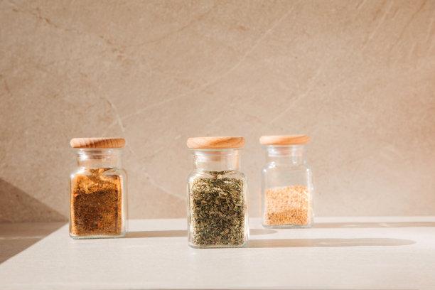 香料在玻璃罐中，浅色的石头背景与阴影。辣椒粉、香草、芥末图片下载