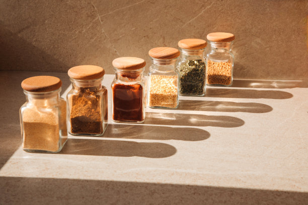 一组调味在玻璃罐中，在浅色的石头背景与阴影。辣椒粉，香草，芥末，大蒜图片下载