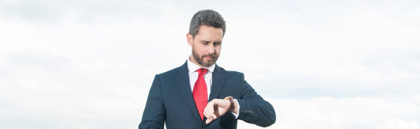 穿着西装的商人在天空背景上检查时间图片下载