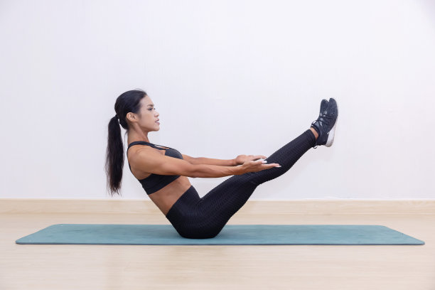在瑜伽垫上摆V形坐姿的女子图片下载