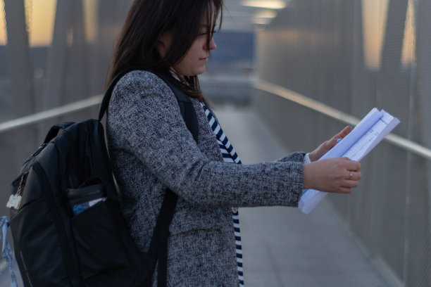 一个年轻的女建筑师的肖像与她的背包审查计划的新建造的桥梁在黎明图片下载