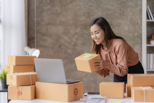 网上中小企业业务和快递概念，微笑的女孩，美丽的老板，亚洲自由职业者，网上购物中小企业业务在笔记本电脑上工作与包裹盒子在家里的桌子上。图片下载