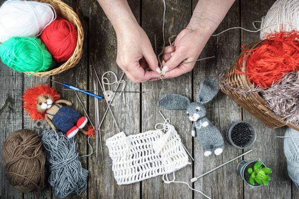 女子在木桌上编织手工纪念品和针织玩具，俯视图图片下载