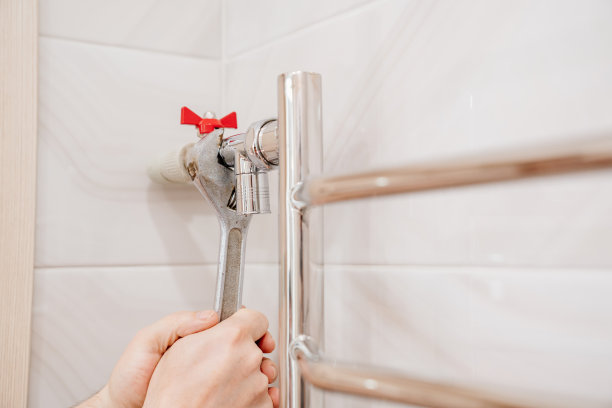 一名男水管工正在修理浴室里加热毛巾架的管道。图片下载