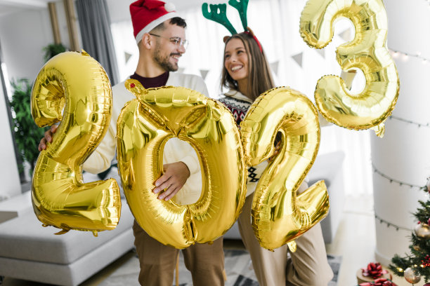 一对夫妇拿着数字2023的大气球在家里庆祝新年图片下载