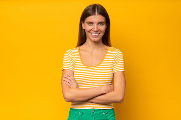 肖像自信的妇女站在孤立的黄色背景与交叉双臂图片下载