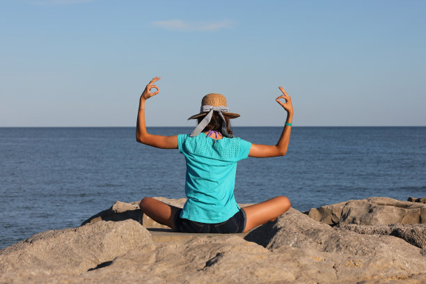 穿着蓝色t恤的苗条年轻女孩在海边做冥想和瑜伽图片下载
