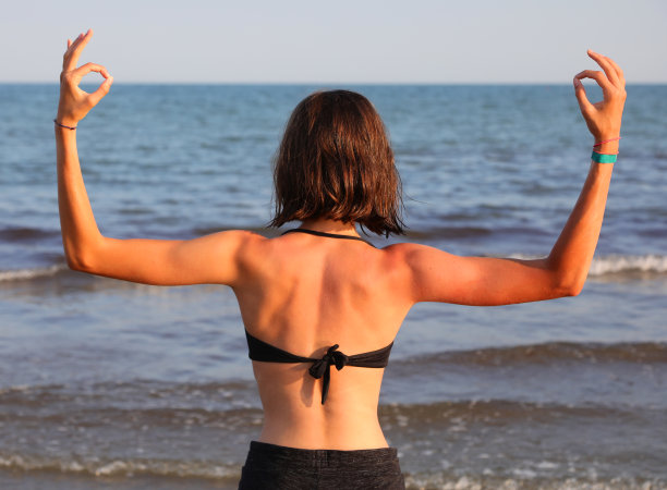夏天在海边做瑜伽时，肌肉发达的女孩有着宽阔的肩膀图片下载