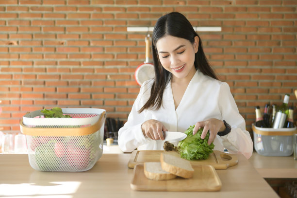 年轻漂亮的白衬衫女人在厨房做饭。图片下载