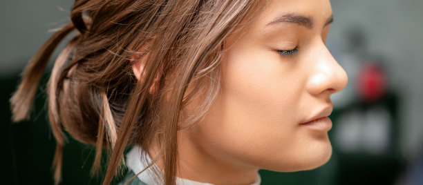 肖像一个性感的年轻白人妇女闭着眼睛显示化妆晒黑她的脸和发型在美容院。图片下载