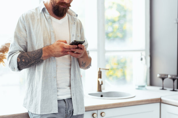 大胡子男人在家里使用智能手机的特写镜头图片下载