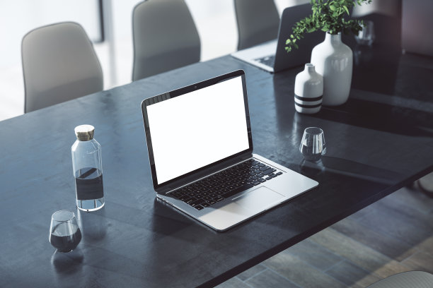 视角上的现代笔记本电脑与空白的白色屏幕与空间为您的标志或文字在黑暗的桌子上的水和花瓶在阳光明媚的办公室。3D渲染，模拟图片下载