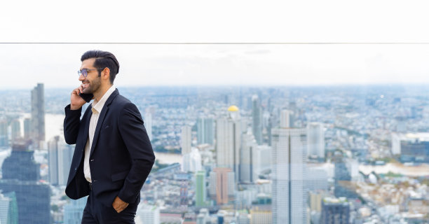 白种人商人在摩天大楼办公室的屋顶上用手机讨论商业项目图片下载
