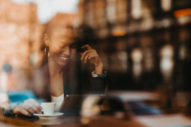 咖啡馆里的女人一边喝着咖啡，一边坐在桌旁谈笑风生图片下载