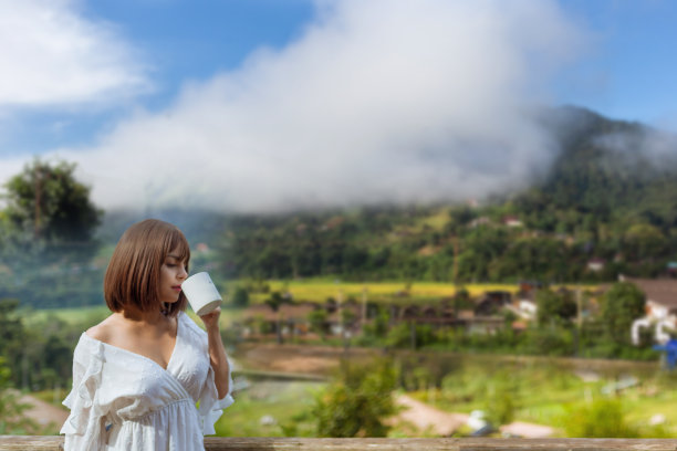 照片上的女人生活起来一杯咖啡，和风景的雾霭覆盖在山上，旅行的概念图片下载