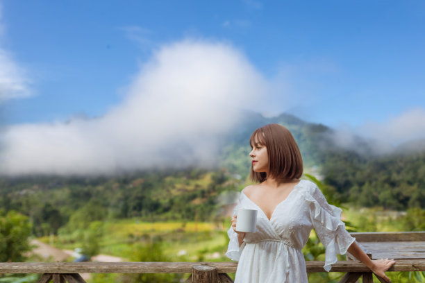 照片上的女人生活起来一杯咖啡，和风景的雾霭覆盖在山上，旅行的概念图片下载
