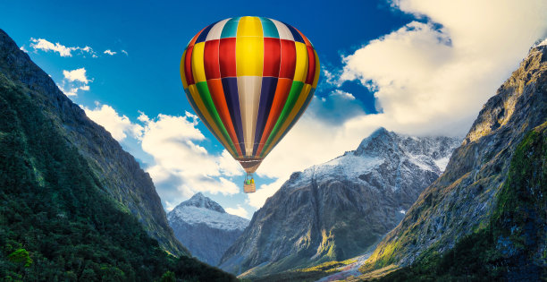 五颜六色的热气球在日出时飞在高山上，天空背景美丽。五颜六色的热气球飞过雪山图片下载