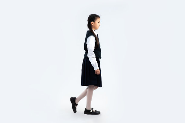 穿着校服的亚洲女学生走在白色背景上。回到学校的概念。图片下载