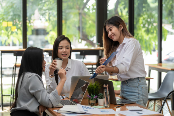 一群年轻的亚洲女商人快乐成功的工作会议头脑风暴使用笔记本电脑，文件被放在办公桌上。图片下载