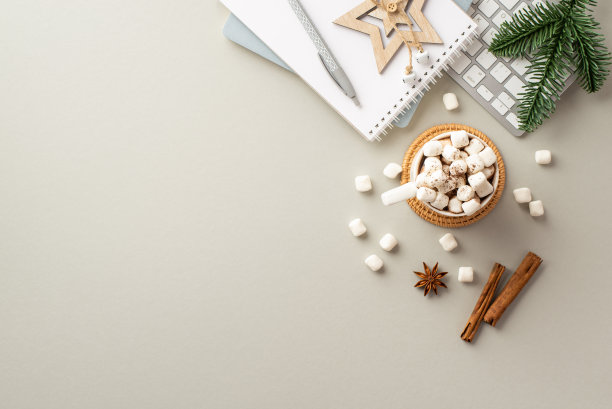 圣诞节的概念。顶视图照片的工作站键盘提醒木明星装饰杯热饮与棉花糖松枝八角和肉桂棒在孤立的灰色背景图片下载