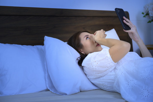 亚洲女性在卧室使用智能手机时感到眼睛疲劳图片下载