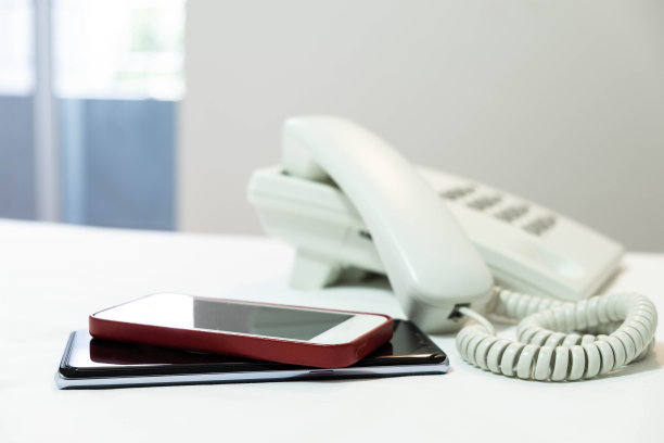 白色床单上的手机和白色按钮电话图片下载